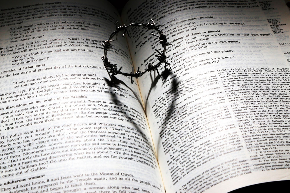 Gottes Wort gibt Kraft, Trost, Freude und Liebe auch in schweren Zeiten! Eine aufgeschlagene Bibel mit Dornenkrone, deren Schatten ein Herz ist.
