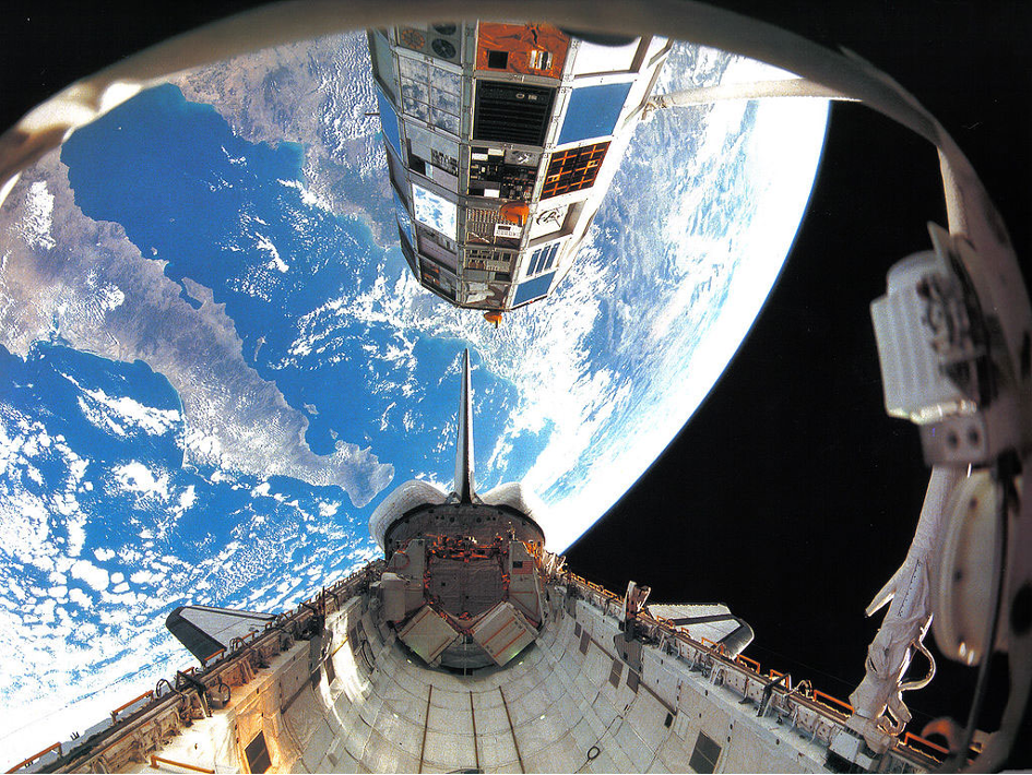 Ein Bild im Weltraum mit Blick auf die Erde - dabei wird der LDEF-Satellit (Long Euration Exposure Facility) ausgeladen